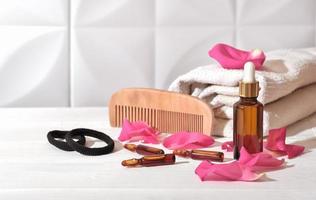 hair loss defying ampules and serum in dropper bottle. oil hair and scalp care next to a towel and comb. photo