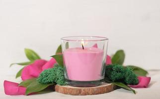 floral fragranced burning candle with green leaves, moss and petals. home fragrances, cozy home ambience, romantic decor for valentines. photo