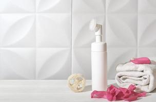 face skin cleaning foam in a white unbranded bottle with brush. delicate skin cleansing. face care concept. copy space. photo