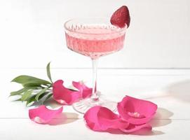 a glass of delicate strawberry wine with berry and rose petals photo