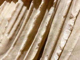 ancient texture. a stone of beige color, a piece of a statue. volumetric texture of stone and sand. a piece of fabric made of stone. fabric waves made by an artisan photo