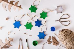 diy adornos navideños hechos a mano estrellas de cartón pintadas con gouache. vista superior. foto