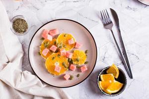 Fruit salad of watermelon, orange and pumpkin seeds on a plate on the table. Healthy food. Top view