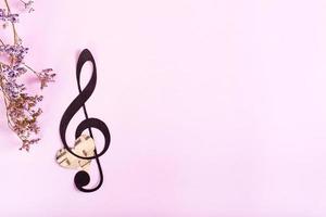Paper musical clef, heart and dry flowers on a pink background. Top view. photo