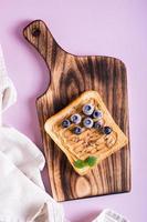 Peanut butter toast with blueberries, flax seeds and mint on a cutting board. Top and vertical view. photo