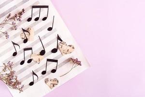 The concept of love for music. Paper notes and hearts on a music sheet. Top view photo