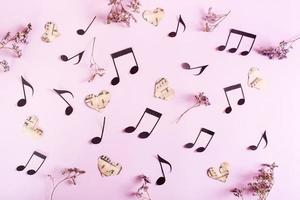 Love music concept. Background from paper hearts, music notes and dry flowers on pink. Top view. photo