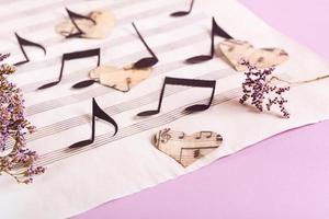 The concept of love for music. Paper notes and hearts on a music sheet. photo