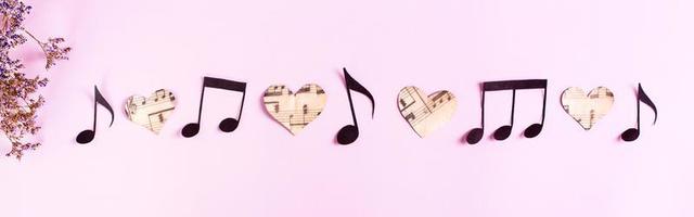 Paper notes and hearts in a row and dry flowers on a pink background. Top view. Web banner photo