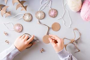 Children's hands cut cardboard circles for DIY Christmas handmade decorations. Top view. photo