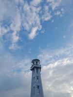 el minarete blanco de la mezquita en la isla de lombok, indonesia, sobre el fondo del cielo azul con nubes blancas. foto