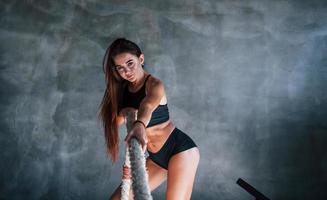 Young fitness woman with slim type of body doing exercises with knots in hands photo