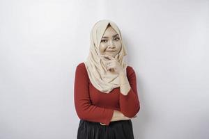 A thoughtful young woman is wearing a hijab and holding her chin isolated by white background photo