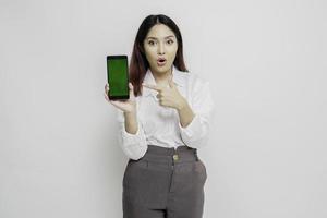 Surprised Asian woman wearing white shirt showing copy space on her smartphone, isolated by white background photo