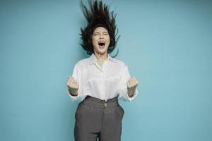 A young Asian woman with a happy successful expression wearing white shirt isolated by blue background photo