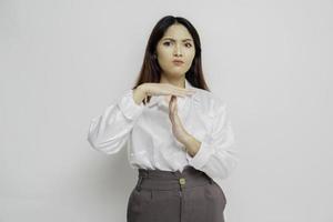 mujer asiática hispana con camisa blanca haciendo gestos de tiempo fuera con las manos, cara frustrada y seria foto