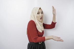 Shocked Asian woman wearing hijab pointing at the copy space beside her, isolated by white background photo