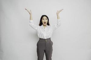 mujer asiática sorprendida con pantalones blanco apuntando al espacio de copia encima de ella, aislada por fondo blanco foto