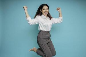 Photo of active Asian girl or employee jump raise hands up wear white shirt isolated blue color background