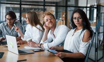 mujer morena frente a los empleados. jóvenes empresarios vestidos de forma formal trabajando en la oficina foto