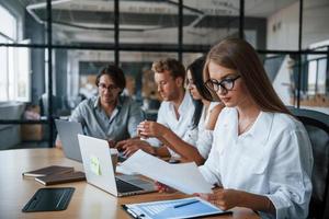 Blonde girl reads document. Young business people in formal clothes working in the office photo