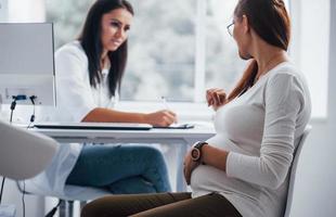 Active conversation. Pregnant woman have consultation with obstetrician indoors photo