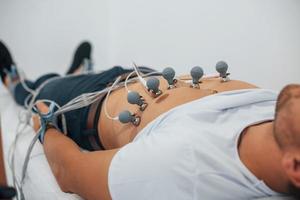 hombre acostado en la cama en la clínica y recibiendo una prueba de electrocardiograma foto