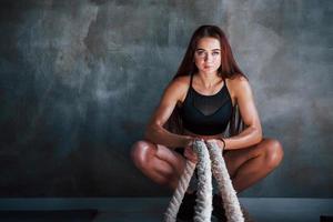 Young fitness woman with slim type of body sits with knots in hands photo