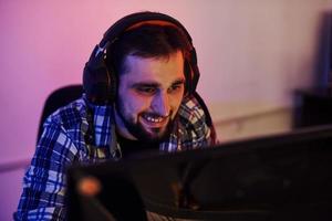 Smiling during the process. Portrait of young bearded pro gamer playing in online video game photo