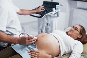 médico masculino hace ultrasonido para una mujer embarazada en el hospital foto