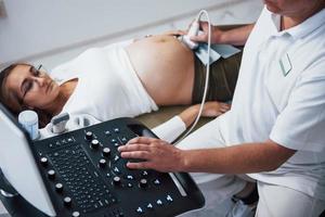 médico masculino hace ultrasonido para una mujer embarazada en el hospital