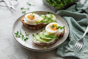 Bread toast, boiled eggs, avocado slice, microgreens on a plate photo