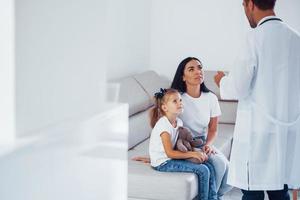 madre con su linda hija está visitando la clínica. escuchando al medico foto