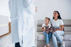 Mother with her cute daughter is visiting clinic. Listening to the doctor photo