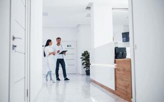 Doctor and brunette nurse walks in the hospital and talking at the work photo