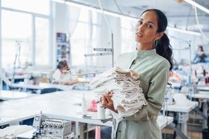 Woman dressmaker stands in the factory with cloth in hands photo