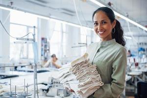 Woman dressmaker stands in the factory with cloth in hands photo