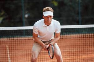 Young tennis player in sportive clothes is on the court outdoors photo