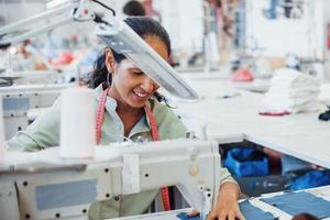 Dressmaker woman sews clothes on sewing machine in factory photo