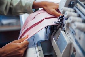 Detailed view of dressmaker woman sews clothes on sewing machine in factory photo