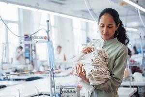 Woman dressmaker stands in the factory with cloth in hands photo