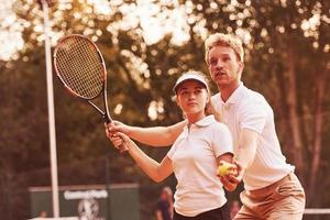 Coach teaching female student tennis game in the court outdoors photo