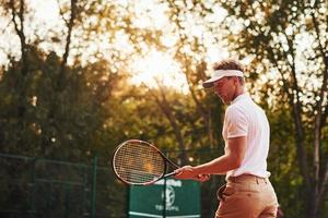 Photo in motion. Young tennis player in sportive clothes is on the court outdoors