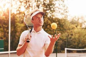 Beautiful sunlight. Young tennis player in sportive clothes is on the court outdoors photo