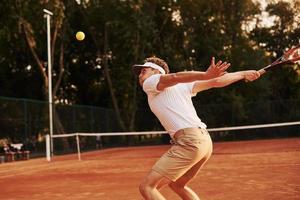 juego en acción. joven tenista con ropa deportiva está en la cancha al aire libre foto