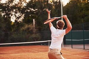 joven tenista con ropa deportiva está en la cancha al aire libre foto