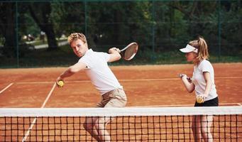 Two people in sport uniform plays tennis together on the court photo