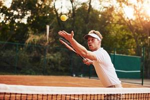 Young tennis player in sportive clothes is on the court outdoors photo