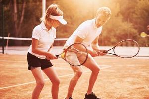 Entrenador enseñando juego de tenis a estudiantes en la cancha al aire libre foto