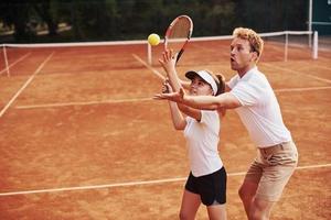 Coach teaching female student tennis game in the court outdoors photo